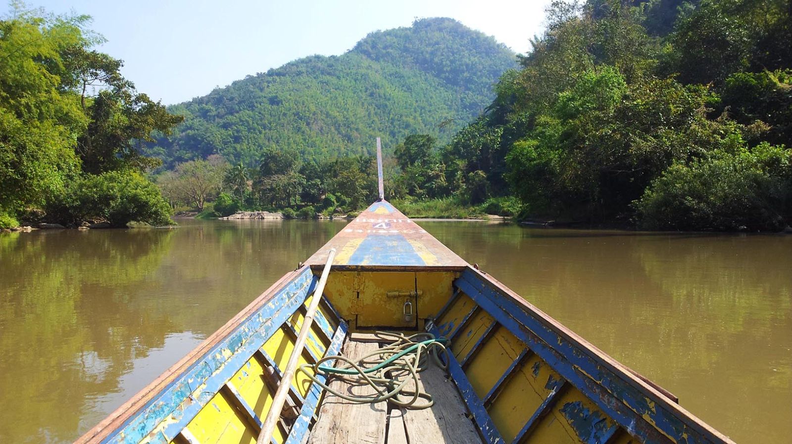 Proue d'un bateau à longue queue sur la rivière Kok entre collines boisées