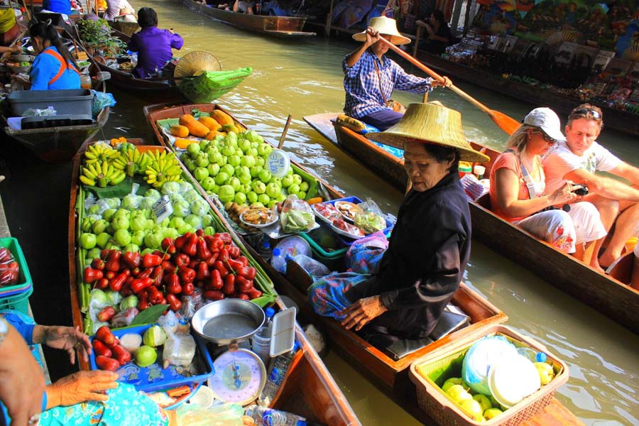 Marchande en chapeau de paille vendant des fruits depuis sa barque à Damnoen Saduak