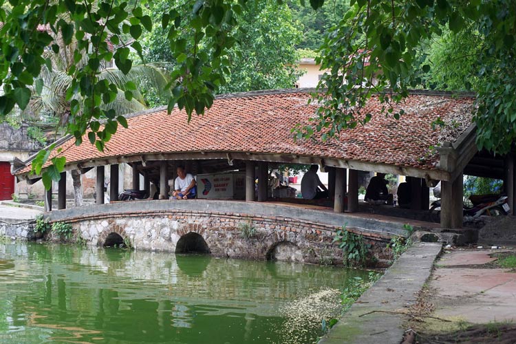 Pont couvert de tuiles sur arches de pierre au-dessus du lac de la pagode du Maître