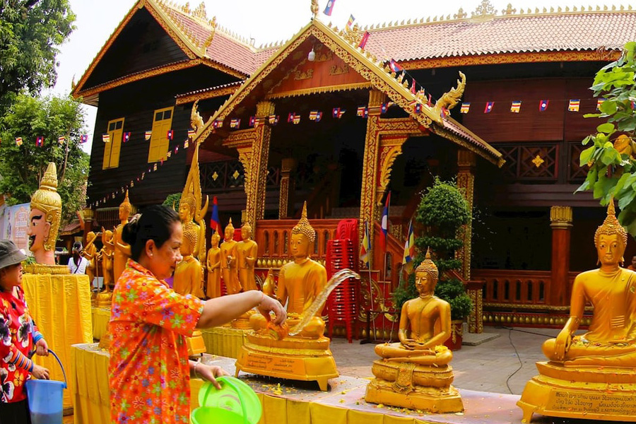 Verser de l’eau parfumée sur une statue de Bouddha au Laos