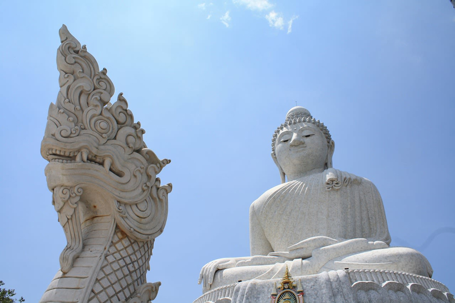 Tête du naga sculpté et visage du Grand Bouddha de Phuket sous le ciel bleu