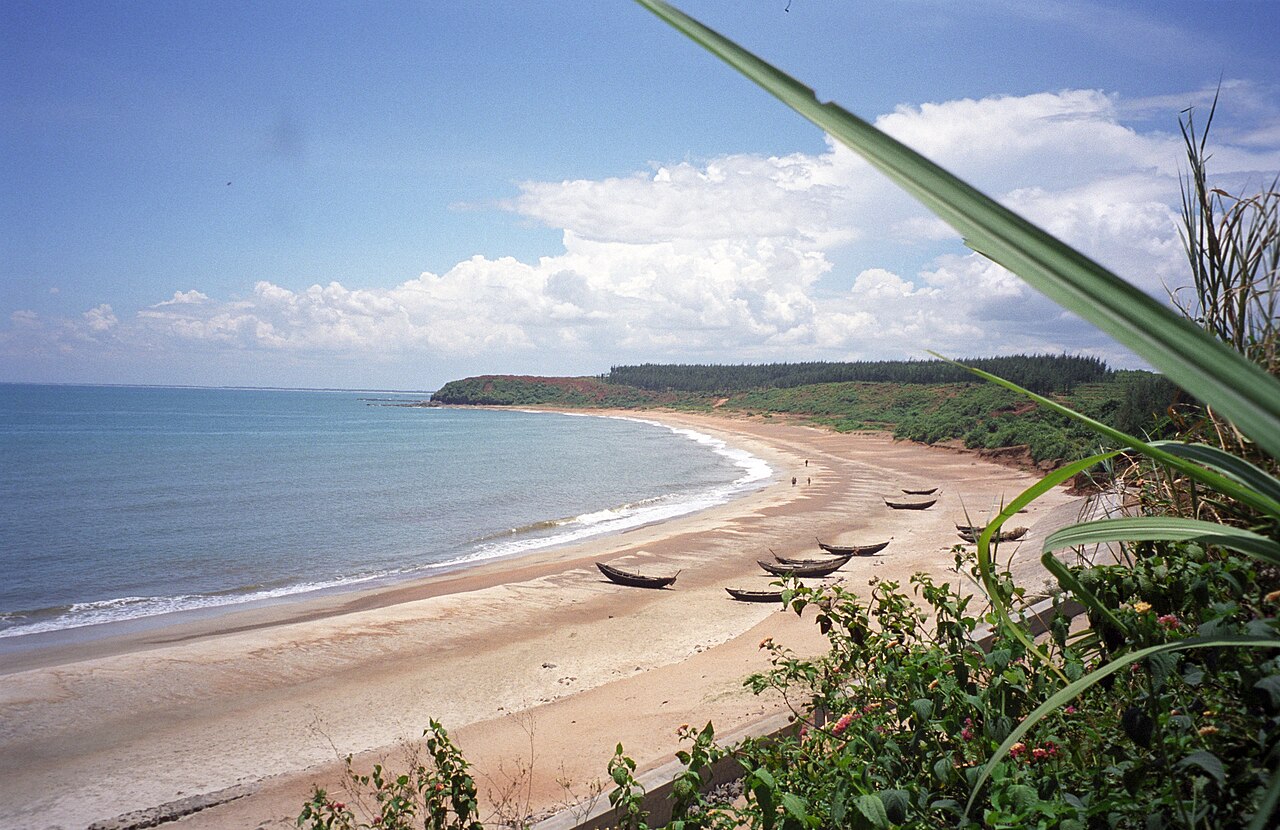 Plage de sable en arc de cercle avec des barques de pêche