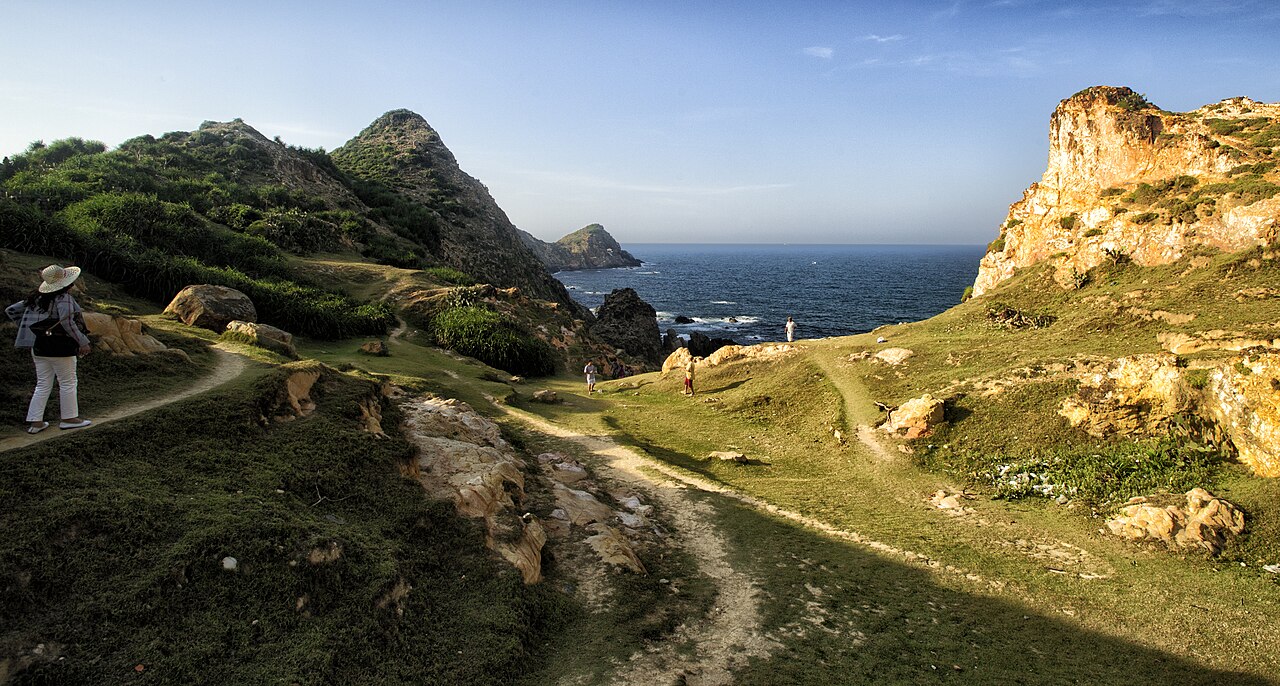 Collines herbeuses et falaises d'Eo Gió dominant une petite baie