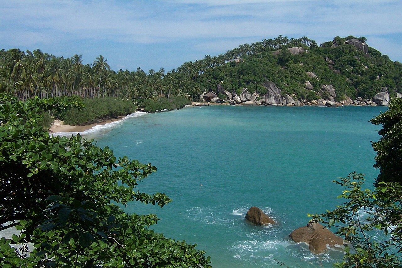 Baie turquoise de Haad Tien bordée de rochers et de cocotiers à Koh Pha Ngan