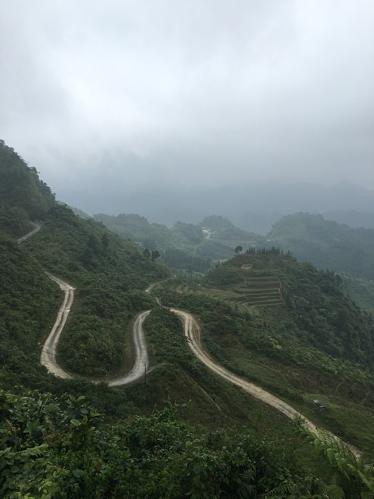 Route en lacets montant vers le col de Quản Bạ dans la brume