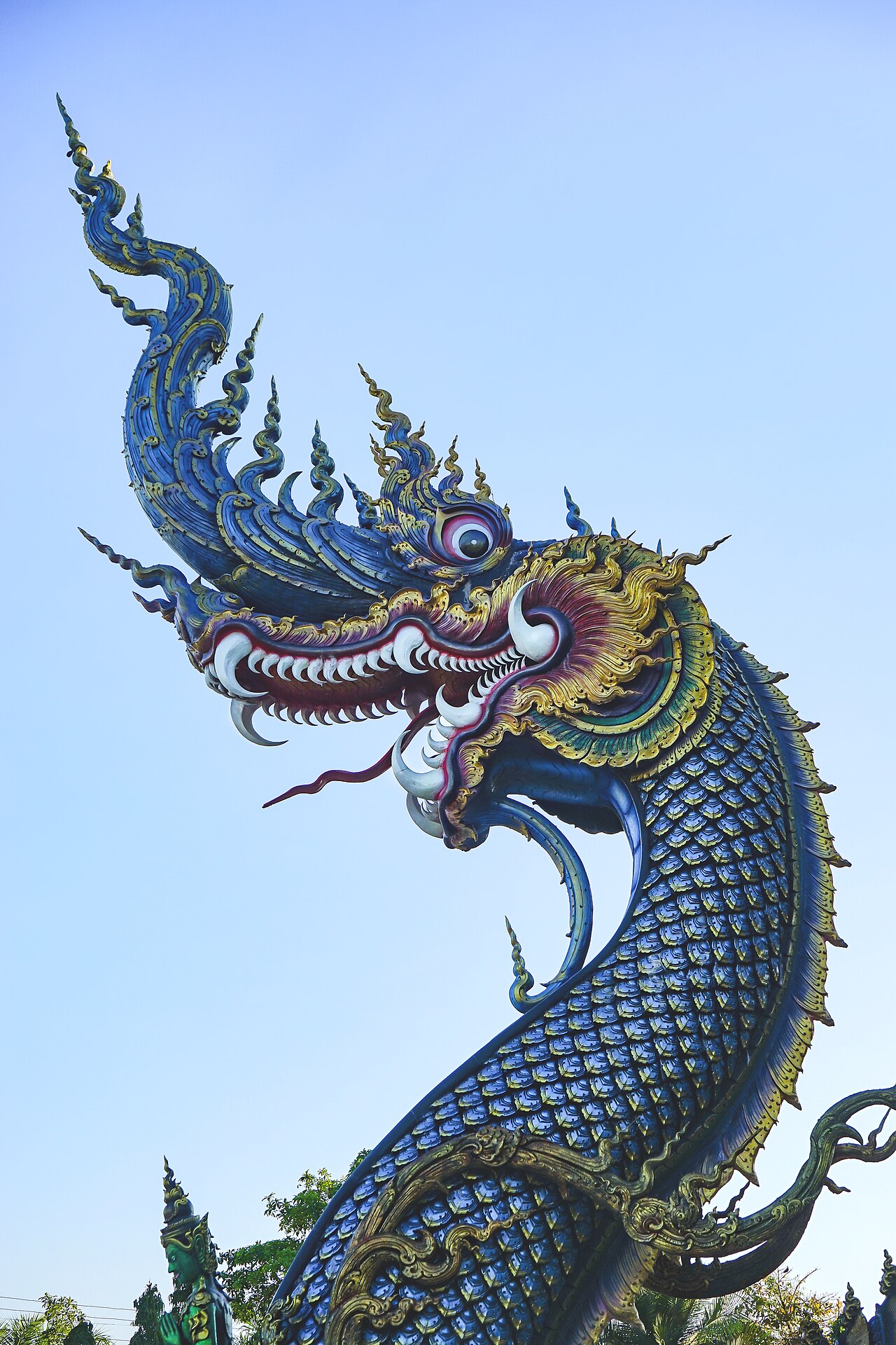 Tête de naga bleu et or aux crocs sculptés sur un escalier du Temple bleu